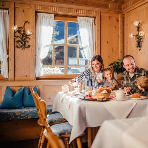 Familie Riezler sitzt in einer rustikalen Almhütte am gedeckten Tisch