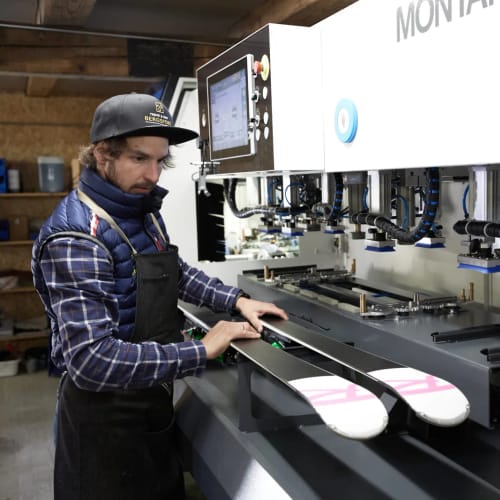 Mann bedient Skibearbeitungsmaschine in der Werkstatt