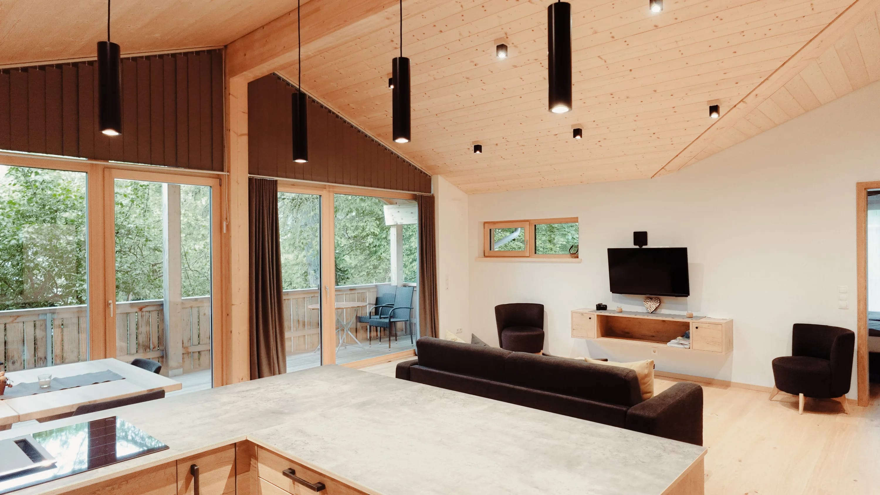 Heller Wohnbereich mit Holzboden und hohen Decken; Sofa, TV-Bank und Zugang zur Terrasse.