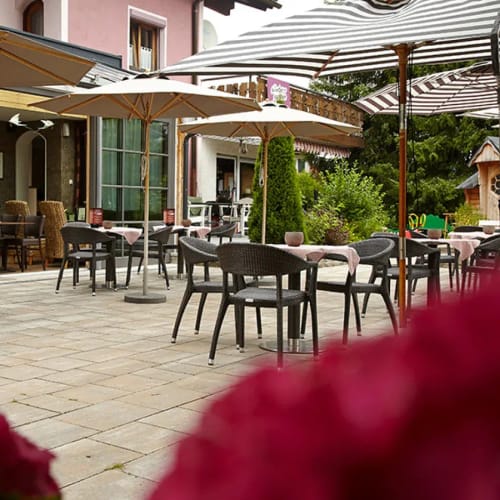 Außenterrasse eines Restaurants mit Tischen, Stühlen und Sonnenschirmen