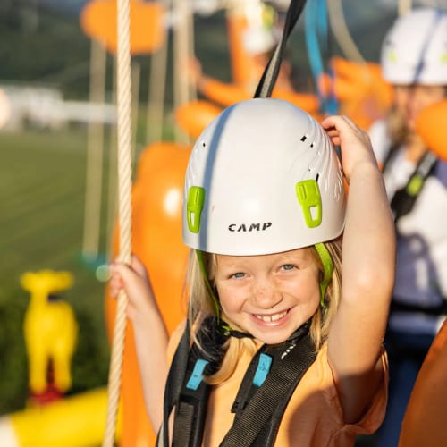 Mädchen mit Helm und Sicherheitsgurt am Hochseilgarten.
