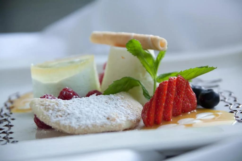 Dessertplatte mit Beeren, weißer Schokolade und Minze, bestäubt mit Puderzucker