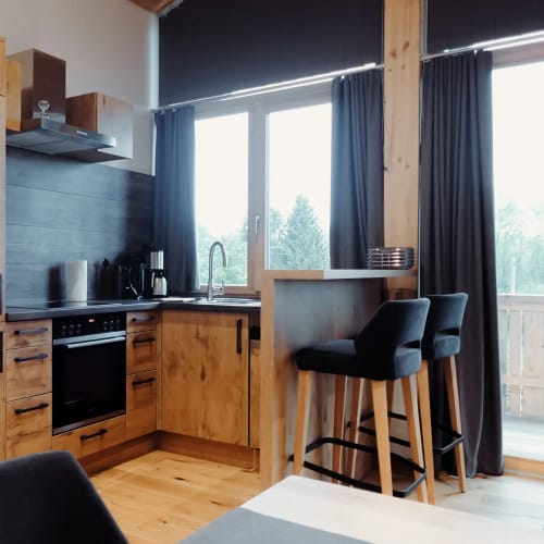 Küche in Holzoptik mit Insel, Barhockern und großen Fenstern