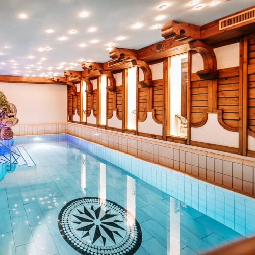 Indoor-Pool im Alpenstueble mit Holzarchitektur, Stein-Dekor und hellen Lichtern