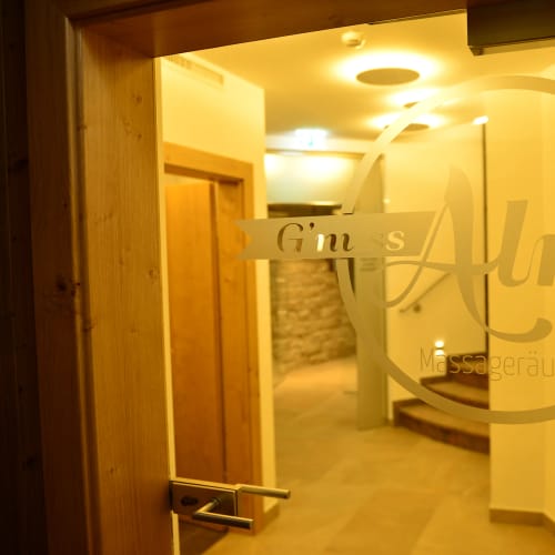 Glas-Tür mit Logo, warm beleuchteter Innenbereich eines Wellnessbereichs sichtbar