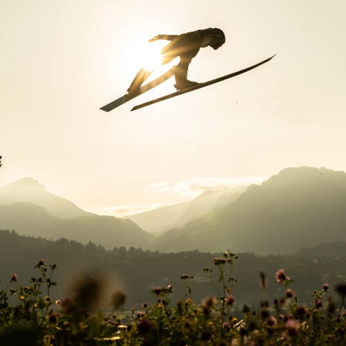 Skispringer springt spektakulär über eine Schanze bei Sonnenuntergang