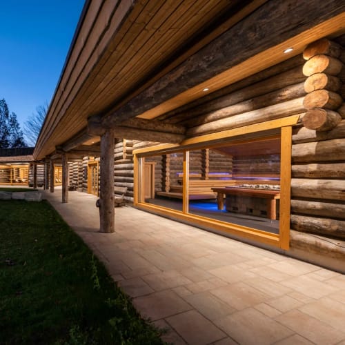 Außenansicht eines Holzkabinen-Sauna-Komplexes mit Glasfront und Terrasse.