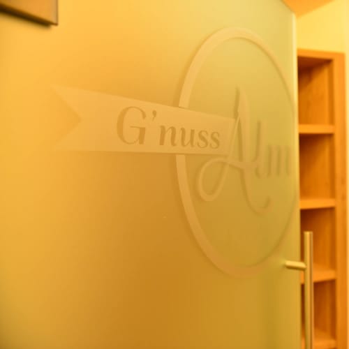 Glastür mit rundem Logo und warmem Innenraum, Regalwürfel sichtbar