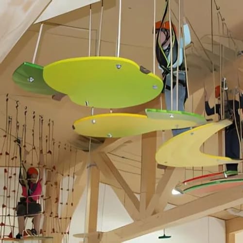 Indoor-Hochseilgarten mit bunten Hänge-Boards und Kletterelementen, mehrere Personen am Seil.