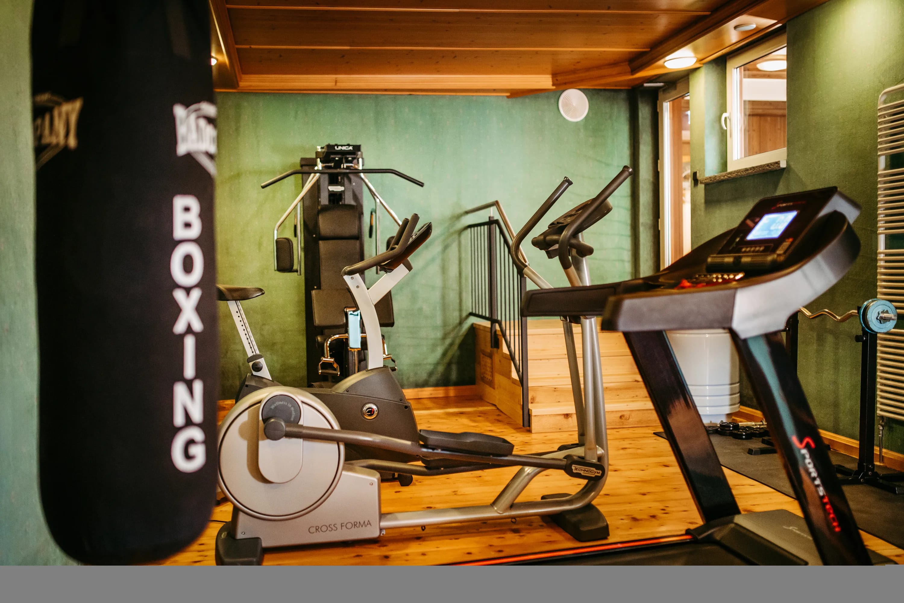 Fitnessraum mit Boxsack, Crosstrainer, Laufband und Rudergerät im Alpenstueble.