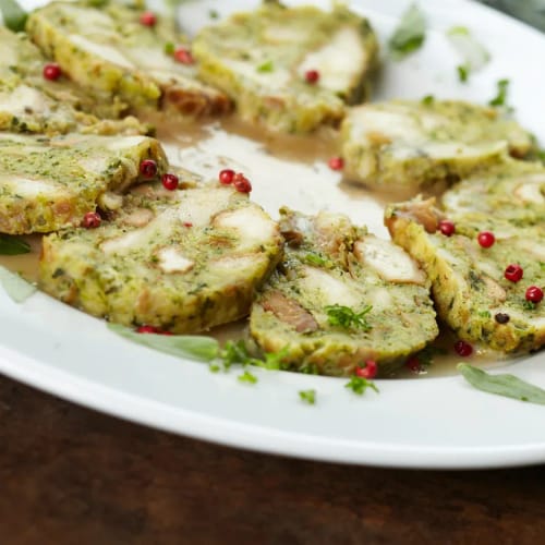 Scheiben von Kräuter-Spinattknödeln auf weißem Teller