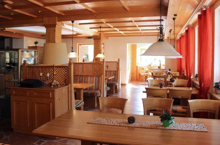 Holzbetonter Restaurantbereich mit Tischen, Stühlen, Trennwänden und warmem Lighting im Alpenhotel
