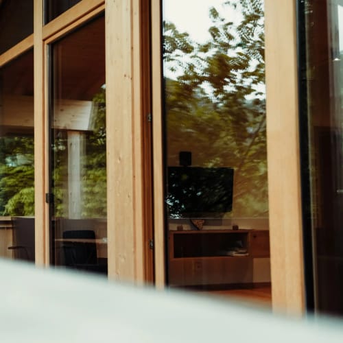 Holzhaus mit Glasfront, Balkon und Terrasse, Blick auf den Garten.
