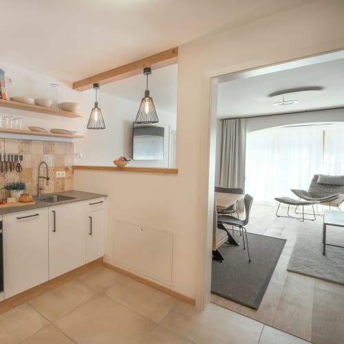 Moderne Küche mit Backofen, Spüle und Pendelleuchten (offene Sicht zum Wohnzimmer)