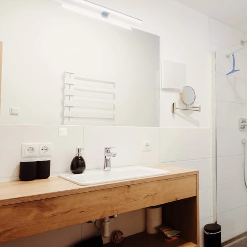 Modernes Bad mit Holz-Waschtisch, Spiegel, Heizkörper und begehbarer Dusche