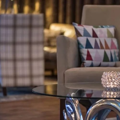 Beiger Sessel in Lobby-Sitzecke, farbiges Kissen, Glastisch mit Kristallkugel-Dekor.