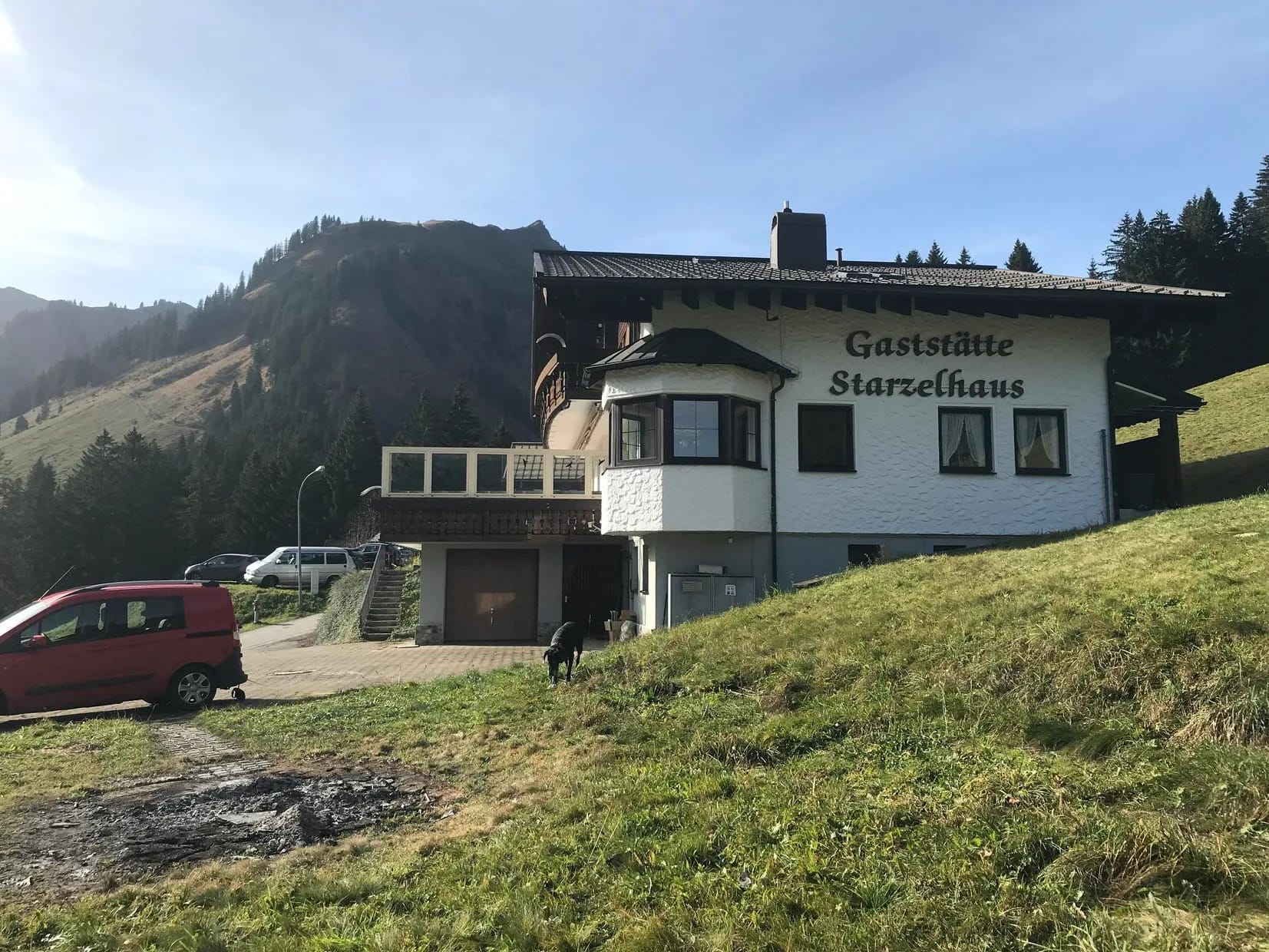 Gästehaus Starzelhaus vor Berghang mit Fahrzeugen am Parkplatz