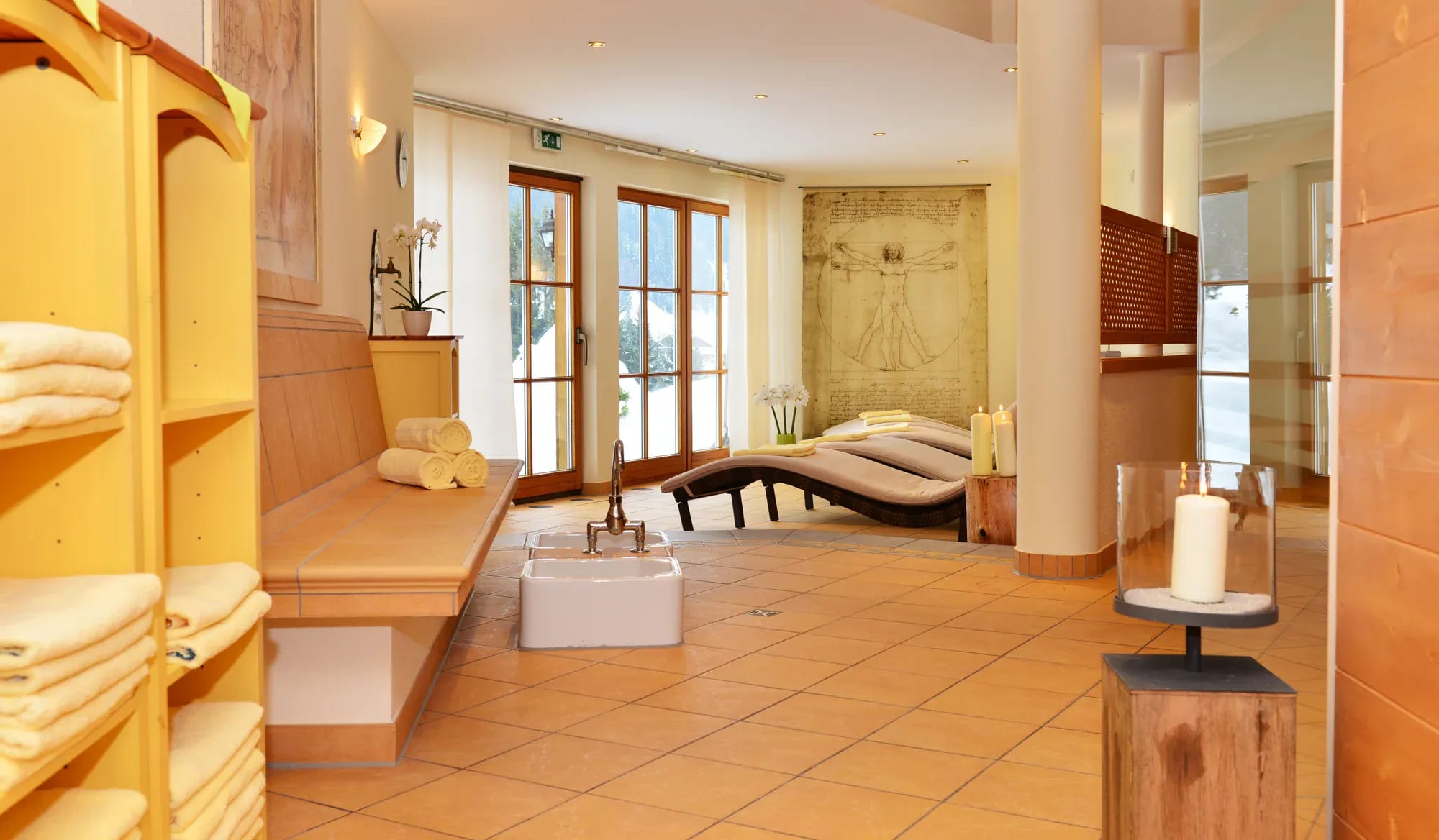 Wellnessraum mit Liegen, Handtüchern, Kerzen und warmen Terrakottafliesen