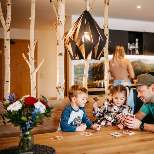 Familie Riezler sitzt am Küchentisch und spielt Karten