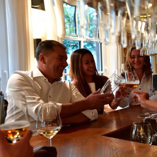 Gruppe von Personen am Bar-Tresen stoßt mit Gläsern an