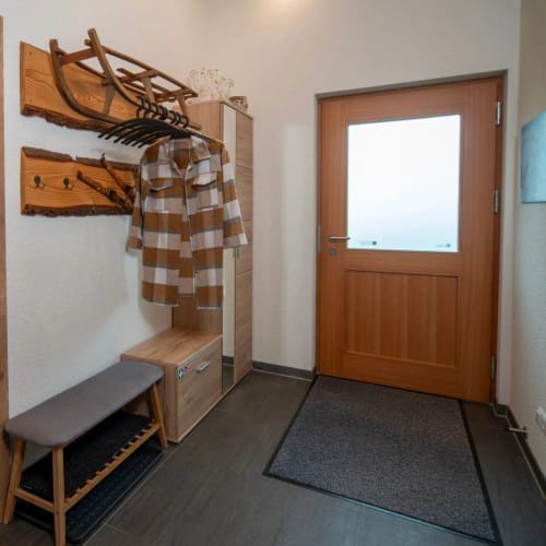Flur mit Garderobe, Mantel, Bank und Eingangstür aus Holz