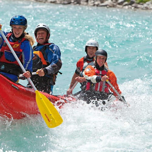 Vier Kanadier-Rafter in einem roten Boot bei Wildwasserfahrt im Allgäu.