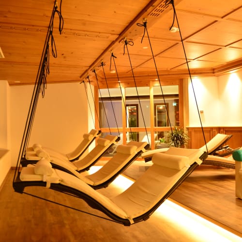 Mehrere hängende Liegen an Seilen im Holz-Wellnessraum.